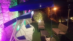 An outdoor seating area with chairs and tables, a stone wall, and a decorative light. - Lovely Appartment in Daroun. Kesserwan (kesrwan)