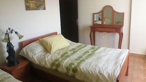 A bedroom with a bed, a nightstand, a dresser, a mirror, and a painting on the wall. - Lovely Appartment in Daroun. Kesserwan (kesrwan)