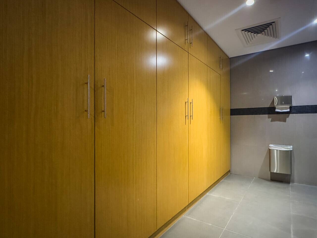 Une salle de bain moderne avec des meubles en bois, un lavabo et une poubelle.