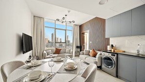 Ein modernes Wohnzimmer mit Essbereich, einer Küche und einem großen Fenster mit Blick auf die Stadt.