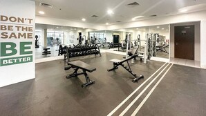 Ein modernes Fitnessstudio mit verschiedenen Trainingsgeräten, einem motivierenden Zitat an der Wand und einem großen Spiegel, der den Raum widerspiegelt.