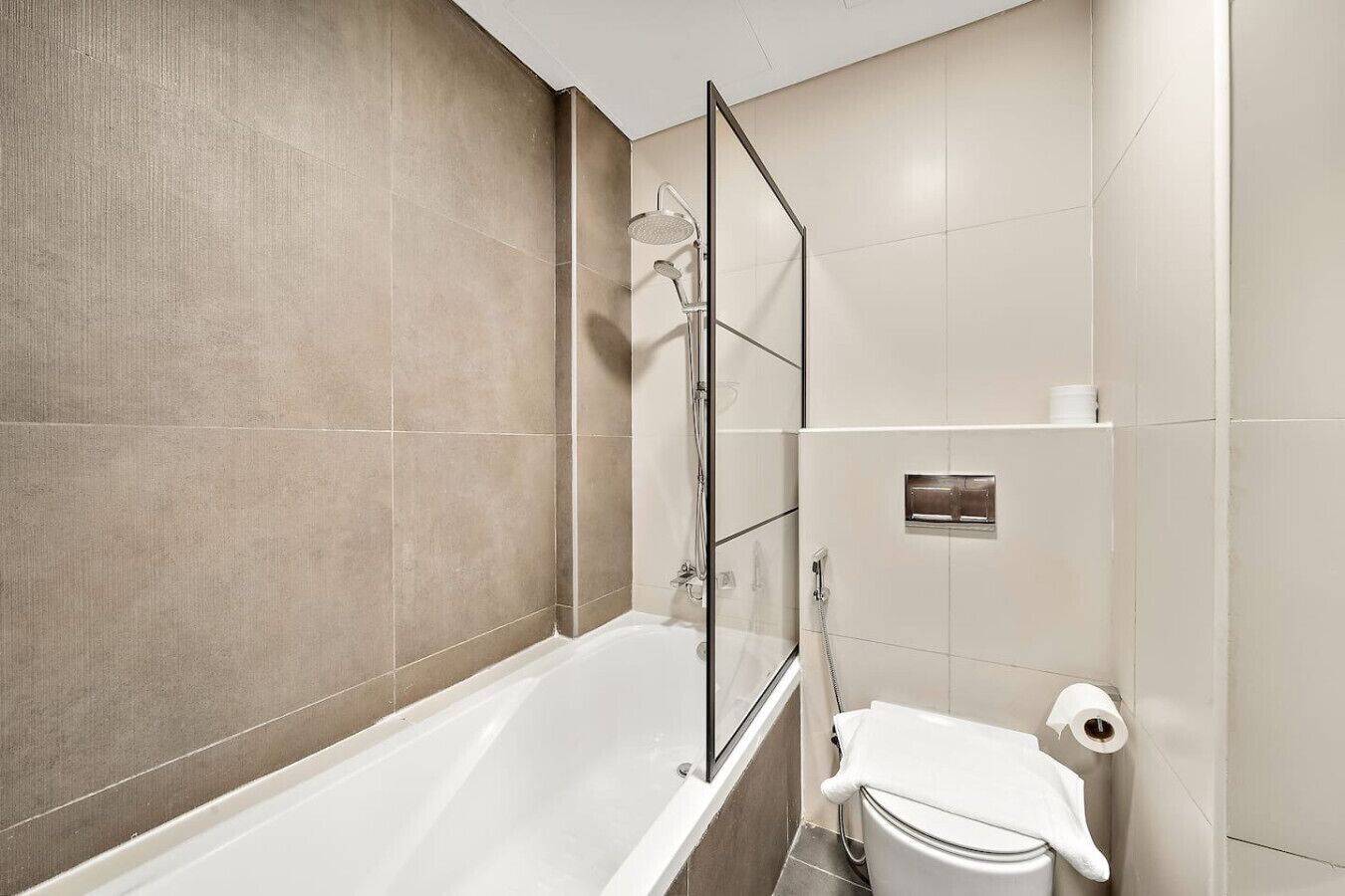 Ein modernes Badezimmer mit einer gläsernen Duschkabine, einer weißen Badewanne und einem WC.