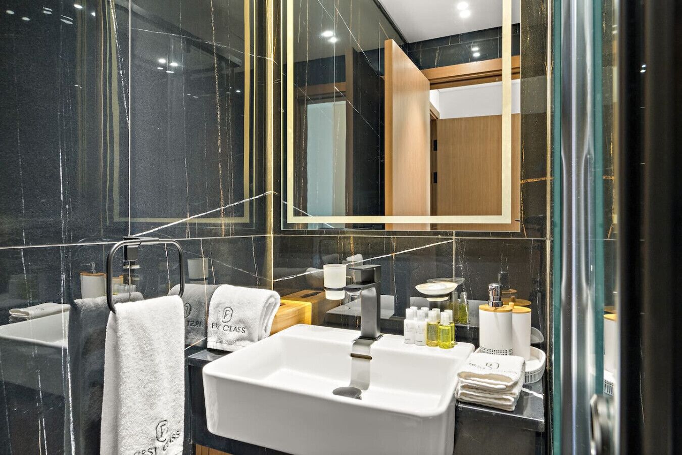 Ein modernes Badezimmer mit einem großen Spiegel, einem weißen Waschbecken und einer Duschkabine aus Glas.