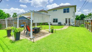 A backyard with a patio, a covered seating area, and a house in the background.