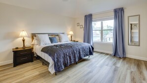 A bedroom with a bed, nightstands, a ceiling fan, a window with curtains, and a mirror on the wall.