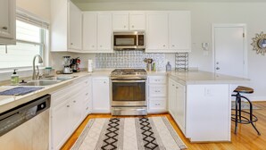 A modern kitchen with white cabinets, stainless steel appliances, and a patterned rug.