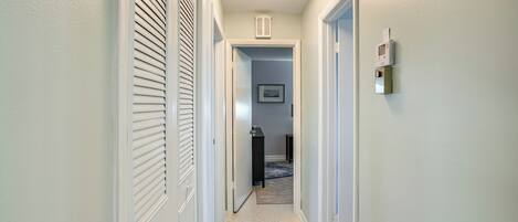A hallway with a door on the left, a door on the right, and a light fixture on the ceiling.