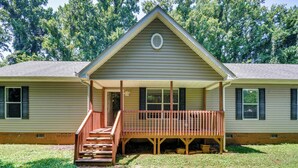 A two-story house with a front porch, a staircase leading to the porch, and a small front yard with stepping stones. - Peaceful Family Retreat in Winston-salem (Winston-Salem)