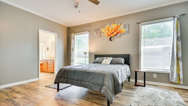 A bedroom with a bed, a nightstand, a window with blinds, and a painting on the wall. - Peaceful Family Retreat in Winston-salem (Winston-Salem)