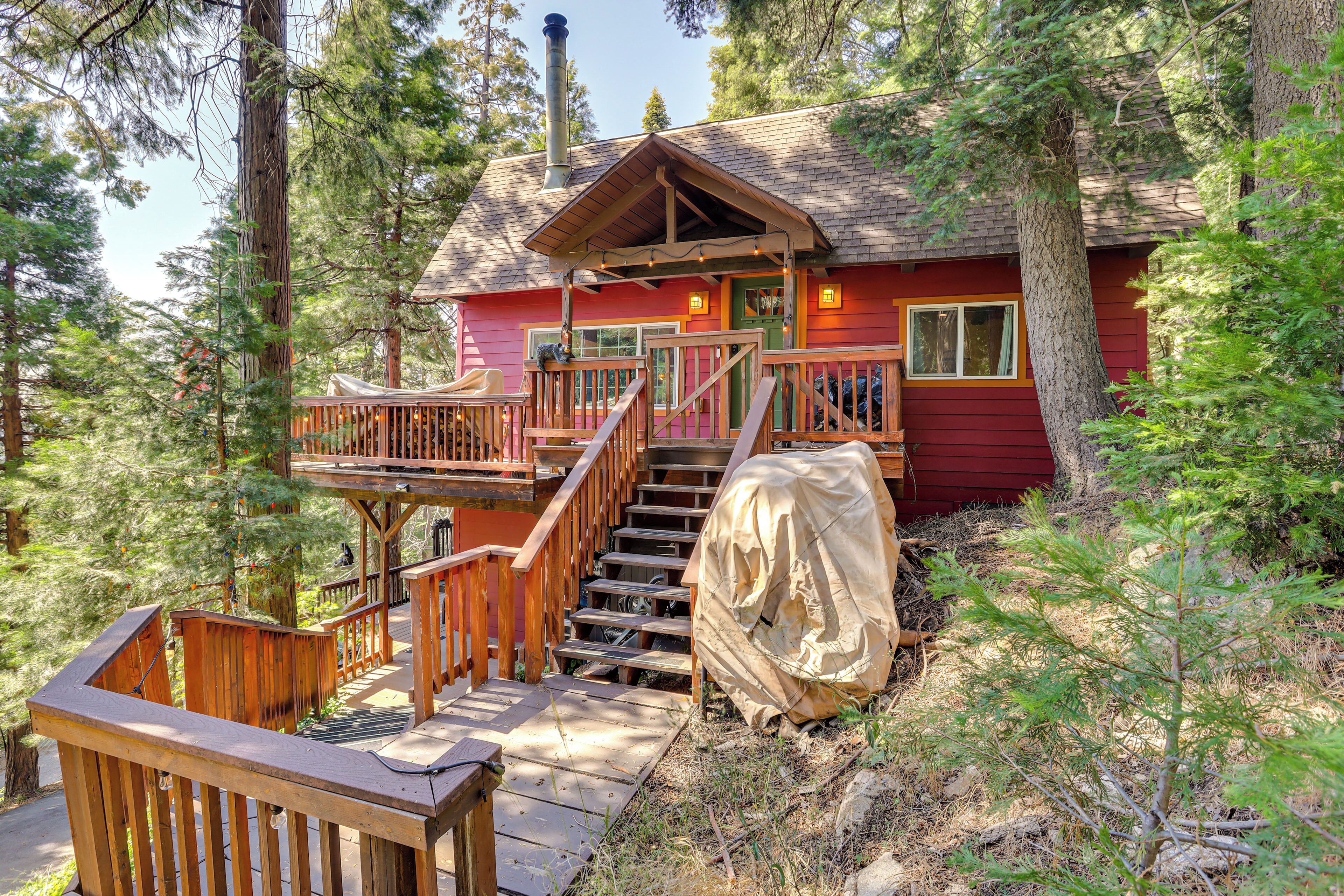A cabin with a wooden deck, stairs, and a covered outdoor seating area.