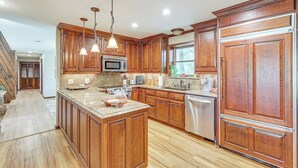 A spacious kitchen with wooden cabinets, granite countertops, stainless steel appliances, and pendant lighting. - Waterfront Home w/ Playground Near Degray & Caddo! (Arkadelphia)