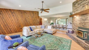 A modern living room with a sectional sofa, a fireplace, and a wooden accent wall. - Waterfront Home w/ Playground Near Degray & Caddo! (Arkadelphia)