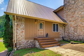Ein Haus mit Steinaußenwand, einem Metall-Dach und einer Veranda mit Stufen zum Eingang.
