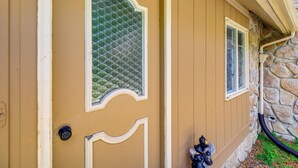 A house with a beige exterior, a decorative glass door, and a stone foundation.