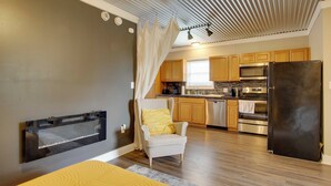 A modern kitchen with wooden cabinets, stainless steel appliances, and a large refrigerator. - 3 Mi to Shops & Eats in Uptown: Greenwood Studio (Greenwood)