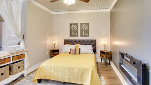 A bedroom with a bed, two nightstands, a ceiling fan, a wall-mounted TV, and two framed pictures. - 3 Mi to Shops & Eats in Uptown: Greenwood Studio (Greenwood)