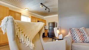 A cozy living room with a beige armchair, a patterned throw pillow, and a small table with a lamp. - 3 Mi to Shops & Eats in Uptown: Greenwood Studio (Greenwood)