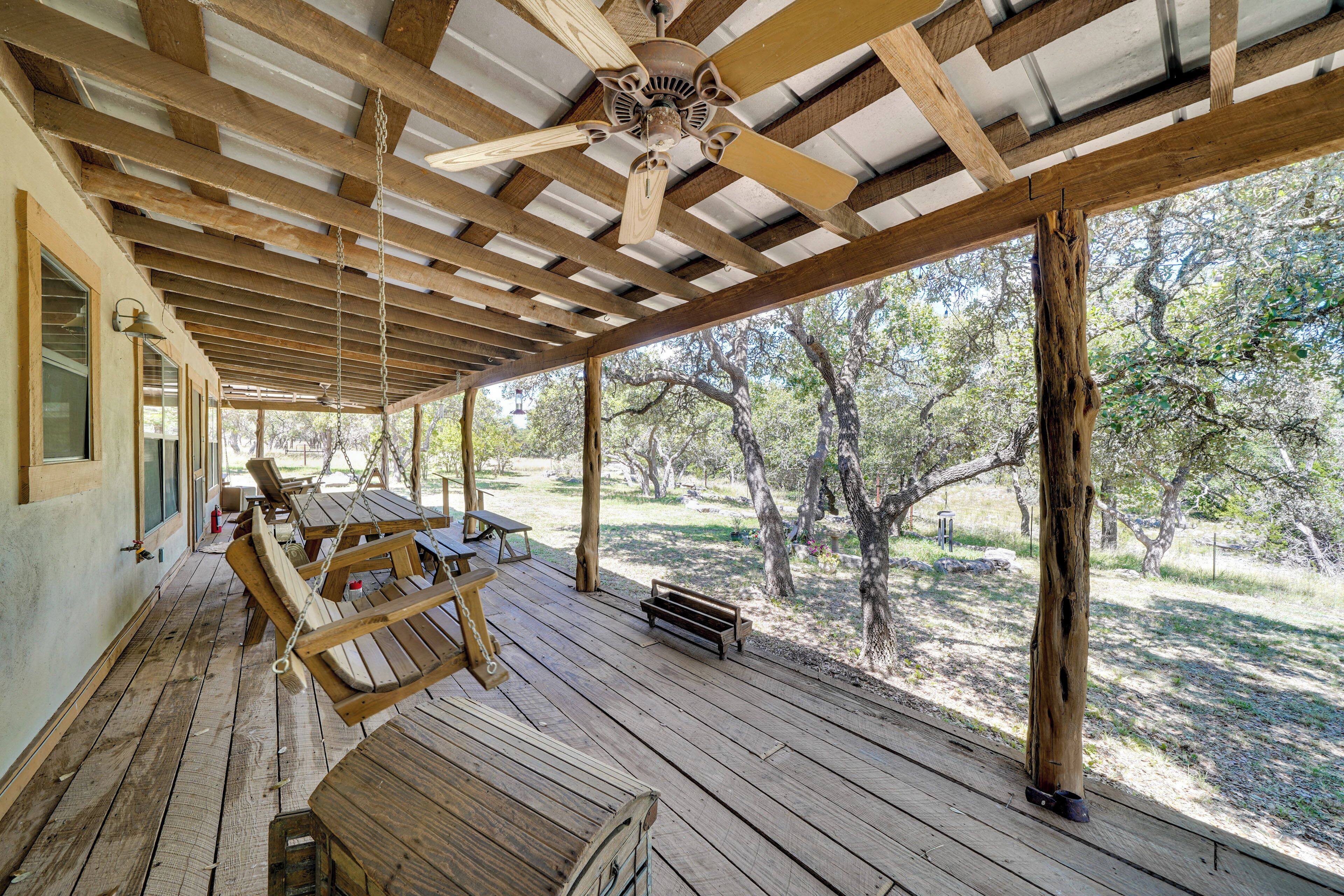 A covered outdoor area with wooden benches and a ceiling fan.
