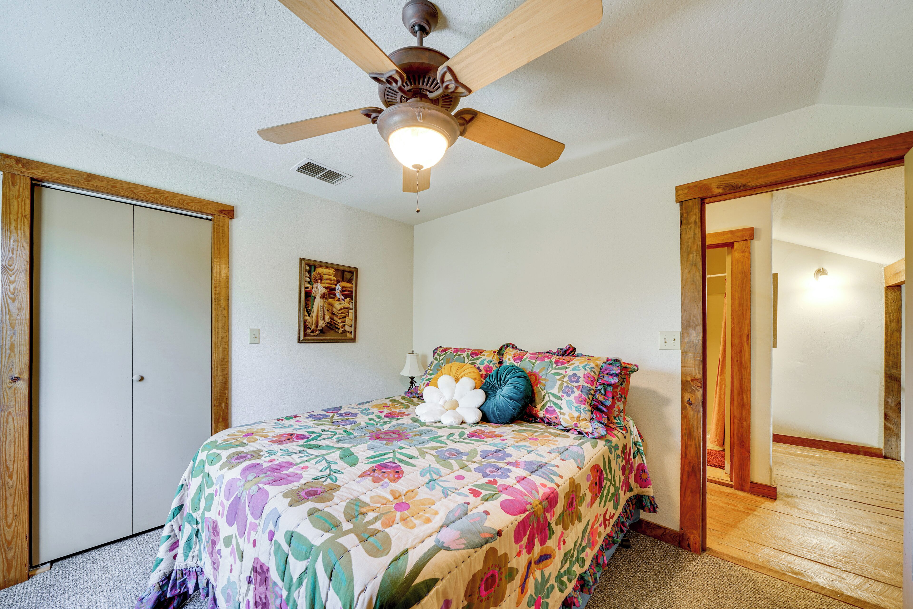 A bedroom with a bed, a ceiling fan, and a wooden door.