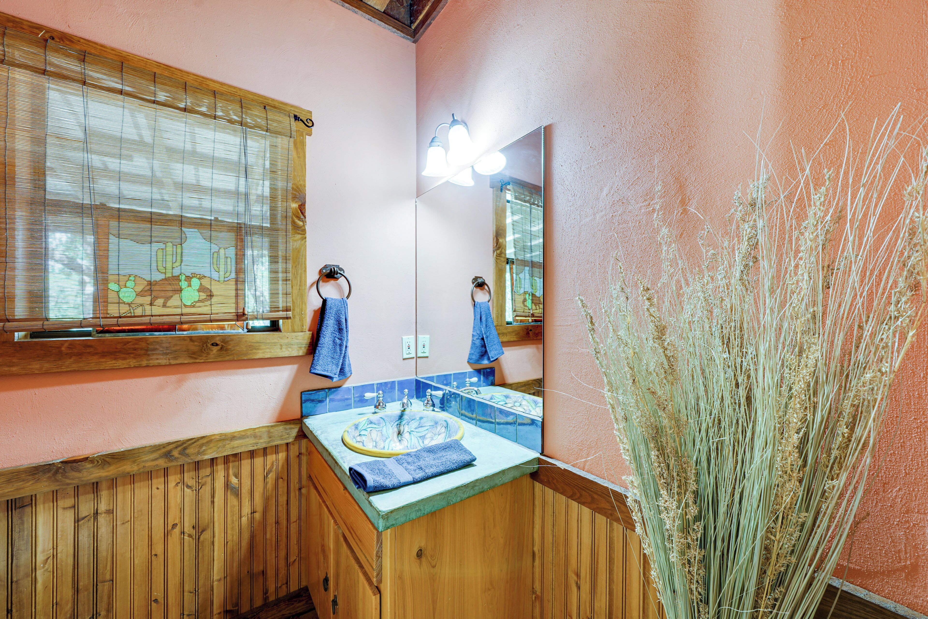 Un baño con paneles de madera, un lavamanos con una toalla azul y un espejo que refleja la habitación.