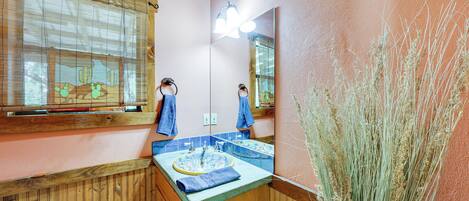 Un baño con paneles de madera, un lavamanos con una toalla azul y un espejo que refleja la habitación.