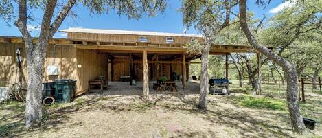 A rustic wooden building with a covered patio area, surrounded by trees.