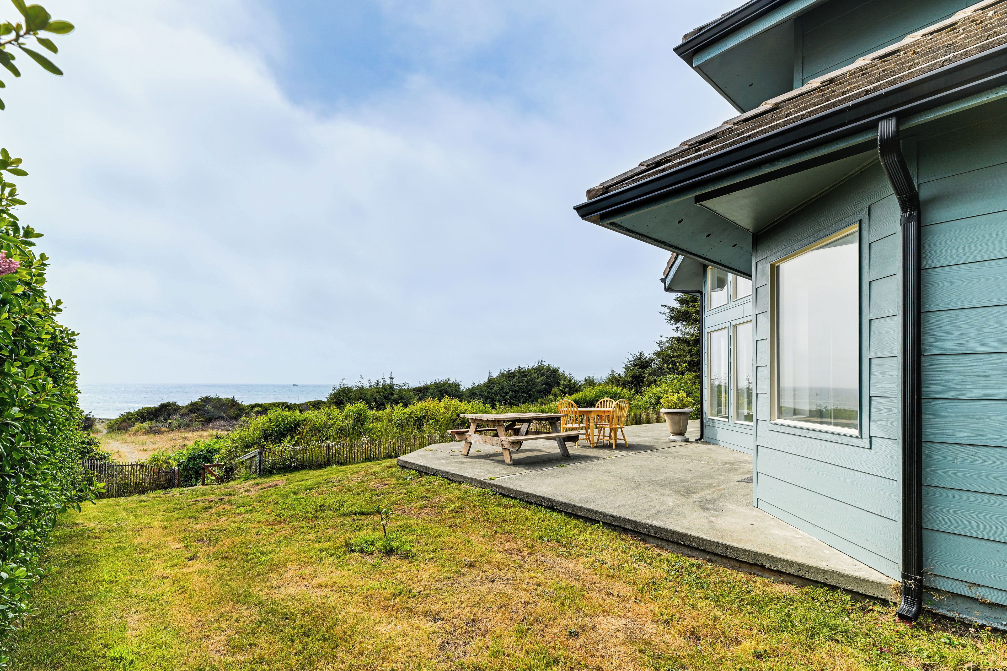 Een huis met een terras, een tafel en stoelen.