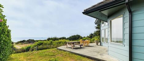 Een huis met een terras, een tafel en stoelen.