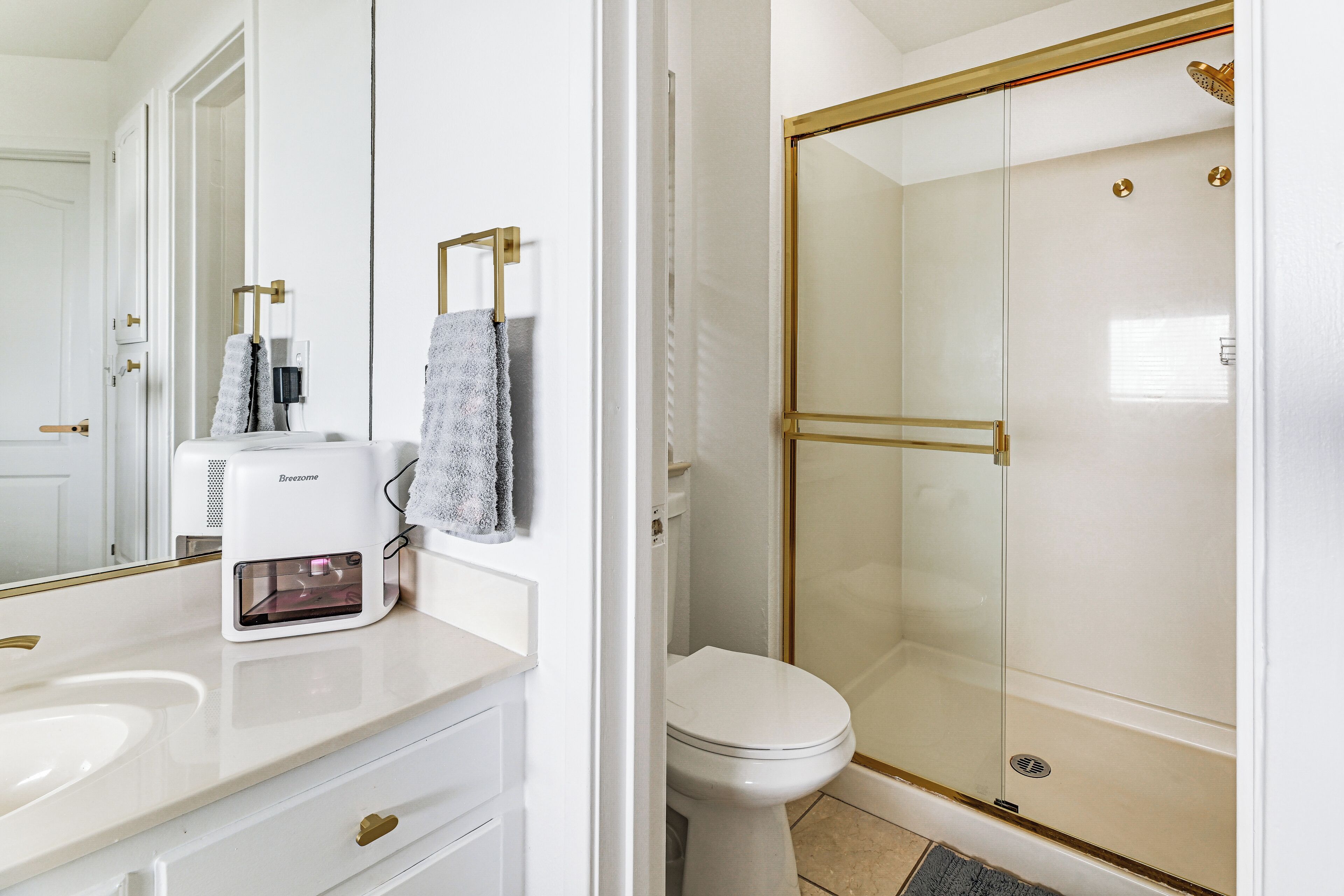 Une salle de bain avec un lavabo blanc, des toilettes et une douche fermée par une paroi de verre.