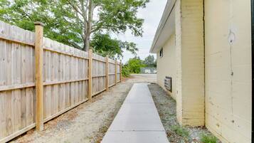 A narrow concrete pathway leading to a building with a yellow exterior wall.