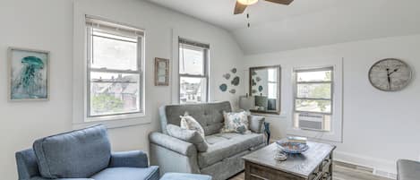 A spacious living room with a grey sofa, a blue armchair, and a wooden coffee table.