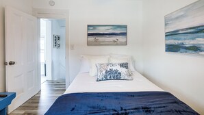 A bedroom with a bed, a painting, and a hallway leading to another room. - Stroll to Ocean Grove Boardwalk & Beach: Sleek Apt (Ocean Grove)