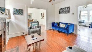 A living room with hardwood flooring, a blue sofa, a grey armchair, and a coffee table. - Home w/ Yard - Close to Hospitals, Dtwn Shreveport (Shreveport)
