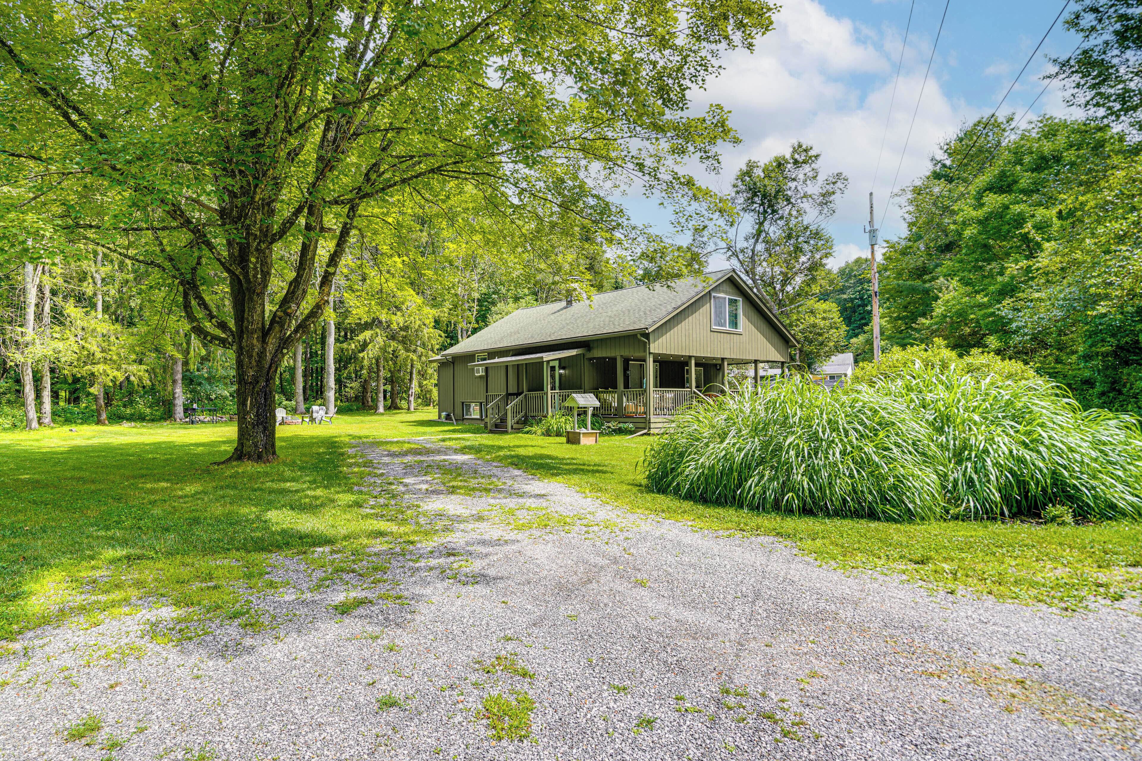 A house with a porch, surrounded by trees and a grassy yard.