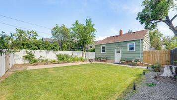 A backyard with a lawn, a wooden deck, and a house.