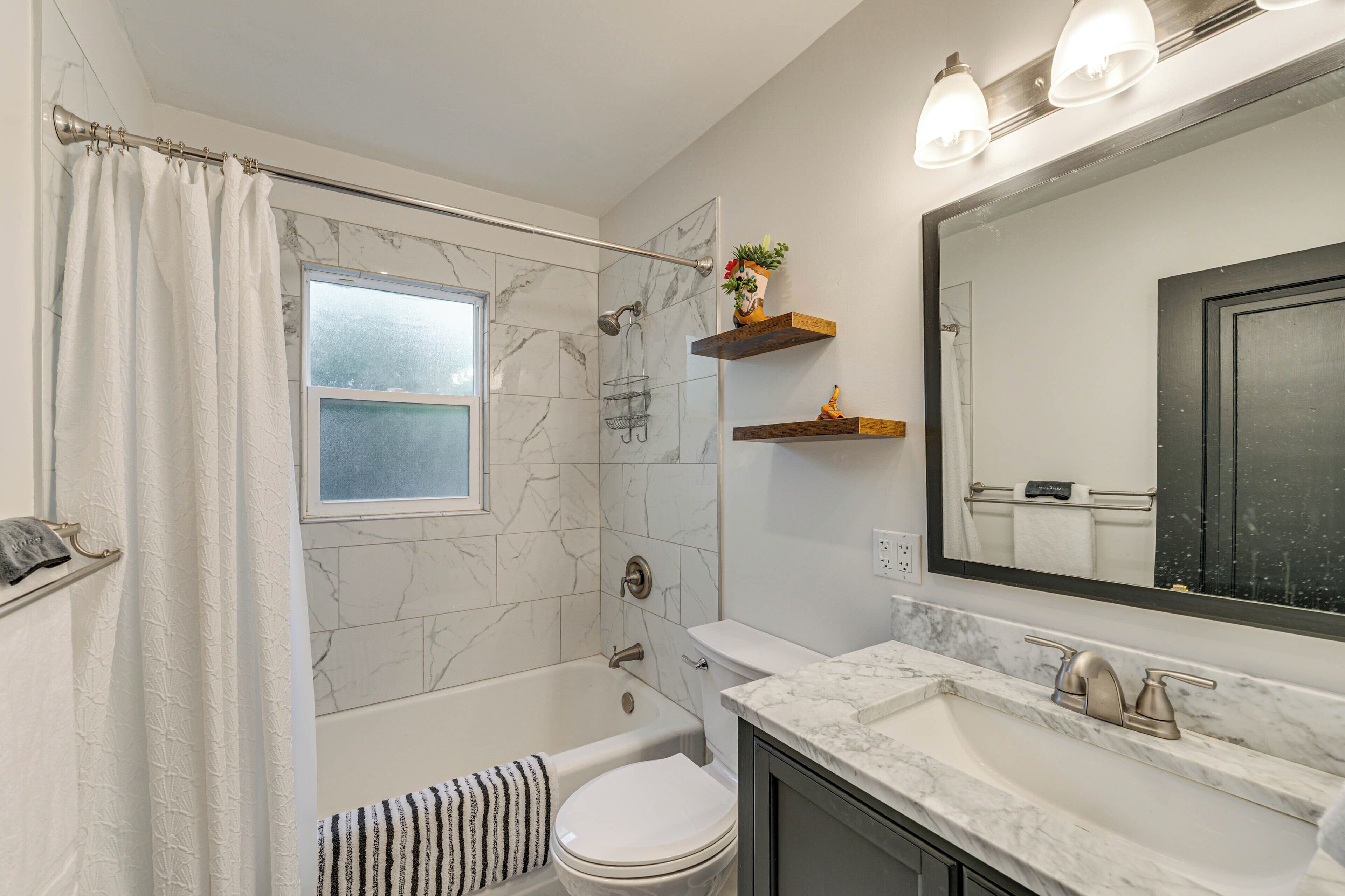 A bathroom with a bathtub, toilet, and a large mirror.