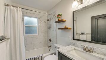 A bathroom with a bathtub, toilet, and a large mirror.