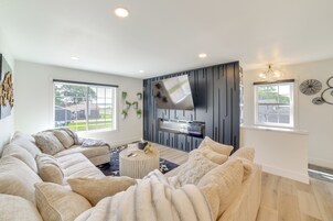 Una sala de estar moderna con un sofá modular, una mesa de centro redonda y un televisor de pantalla plana montado en una pared oscura.