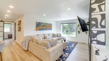 A modern living room with a beige sectional sofa, a coffee table, and a large window.