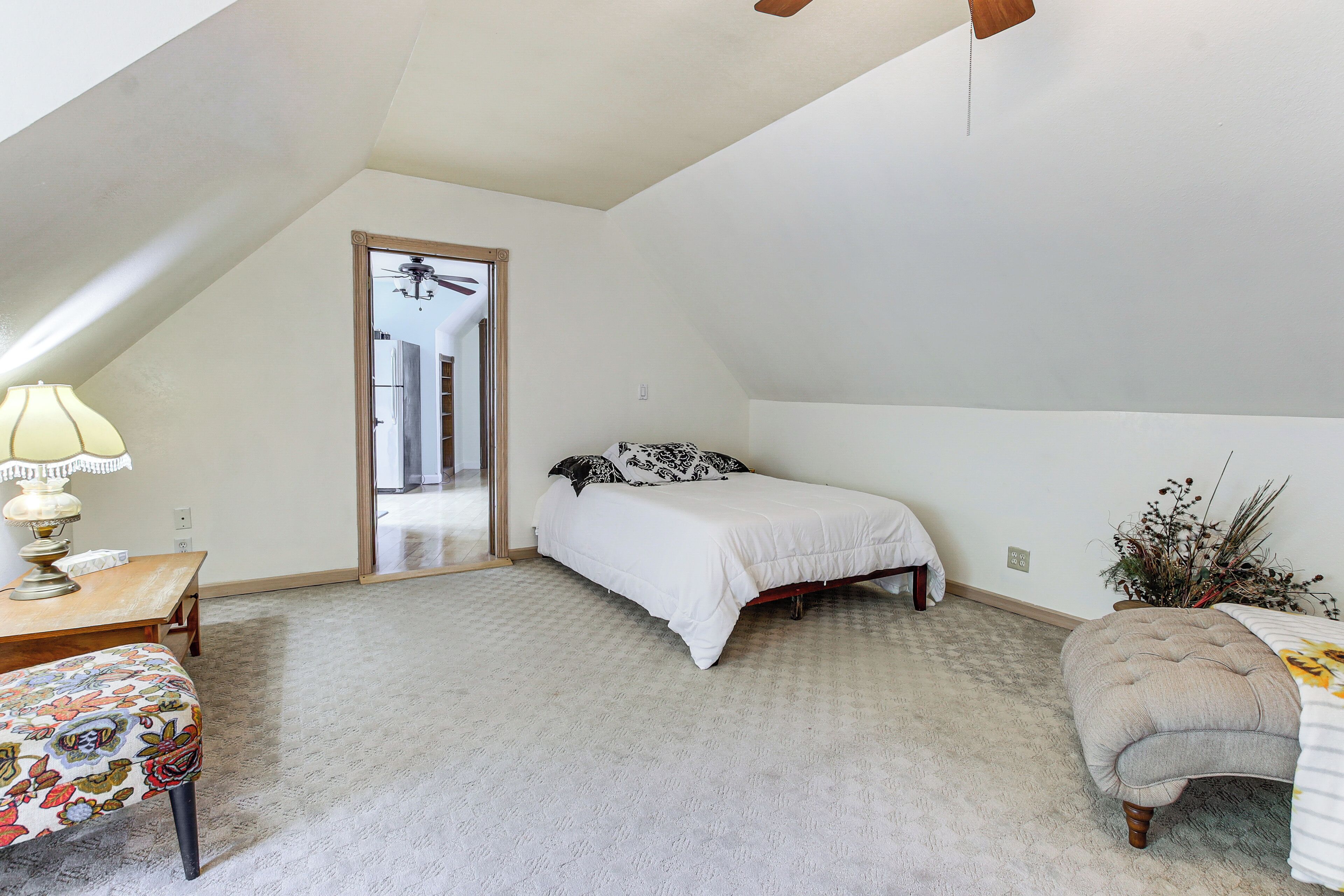 A bedroom with a single bed, a chair, a desk, and a ceiling fan.