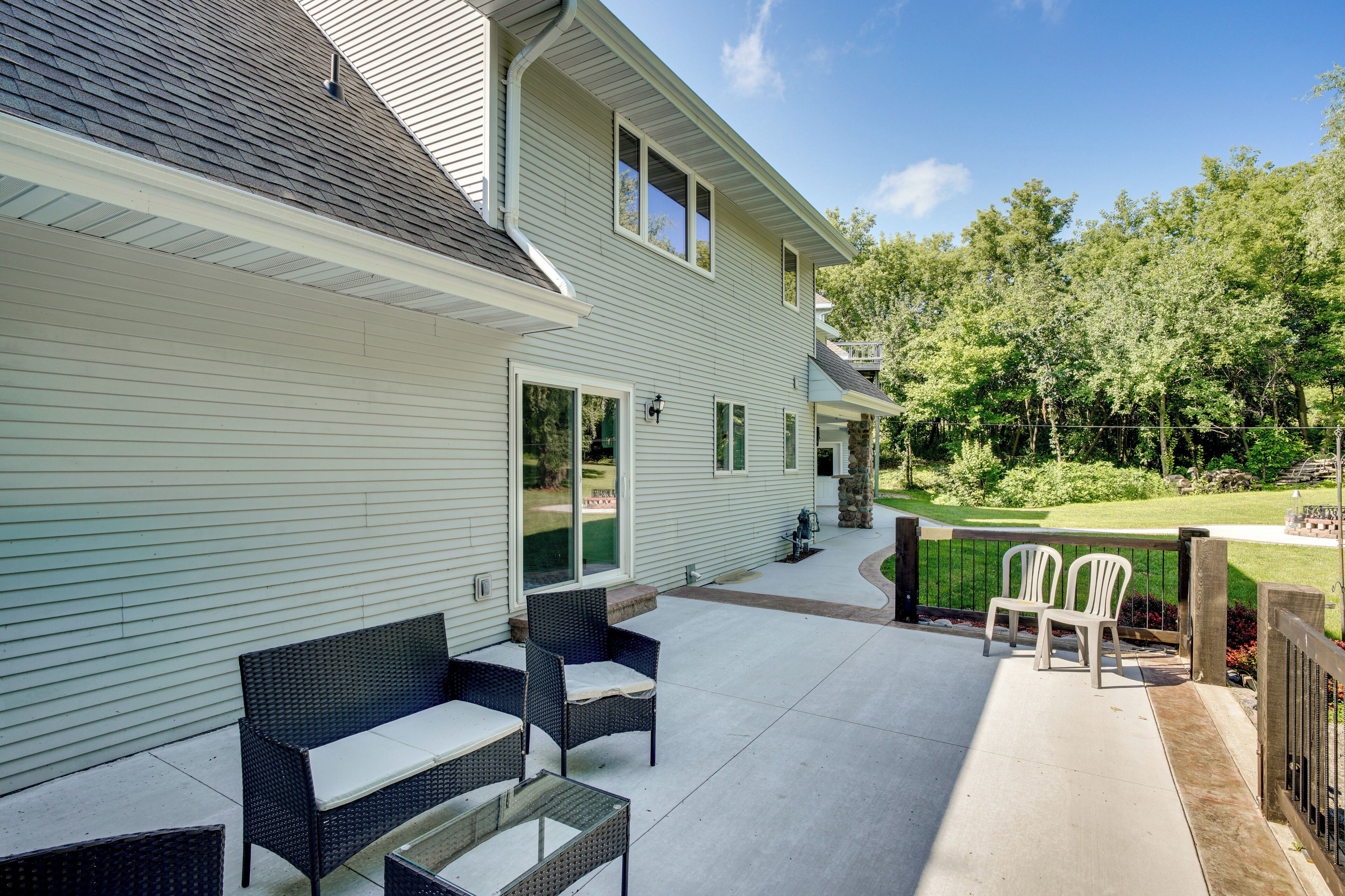 A covered patio with wicker furniture, a small table, and a white chair.