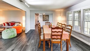 A dining area with a wooden table and chairs, a sofa, and bean bags.