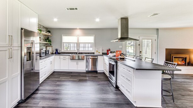 A modern kitchen with white cabinetry, stainless steel appliances, and a central island.