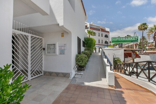 A white building with a gated entrance, a staircase leading to a second floor, and a sign for 'SUPERMARKETS Michel.'