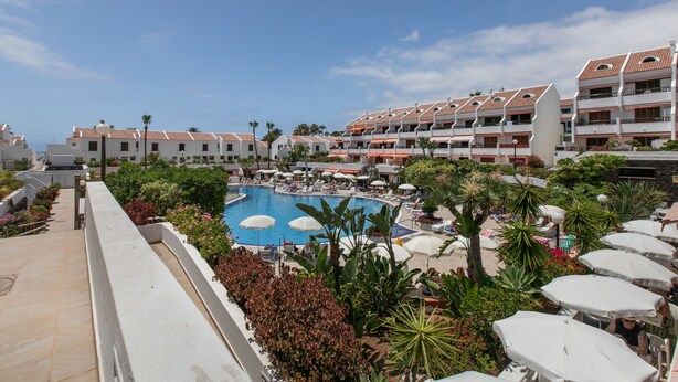 Ein Hotel mit Pool, Sitzgelegenheiten im Freien und Meerblick.