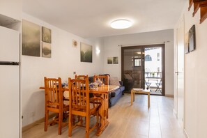 Un coin repas avec une table et des chaises en bois, un canapé et une petite table. Des tableaux sont accrochés aux murs et un luminaire est fixé au plafond.