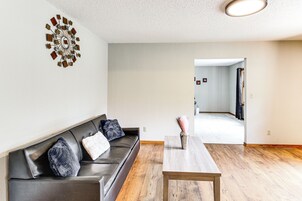 Una sala de estar moderna con un sofá de cuero oscuro, una mesa de centro de madera y un adorno en la pared.
