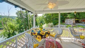 A covered outdoor patio with a table and chairs, surrounded by a white lattice fence, overlooking a lush green landscape. - River Views & Boat Launch Access: Huntingdon Home (Huntingdon)