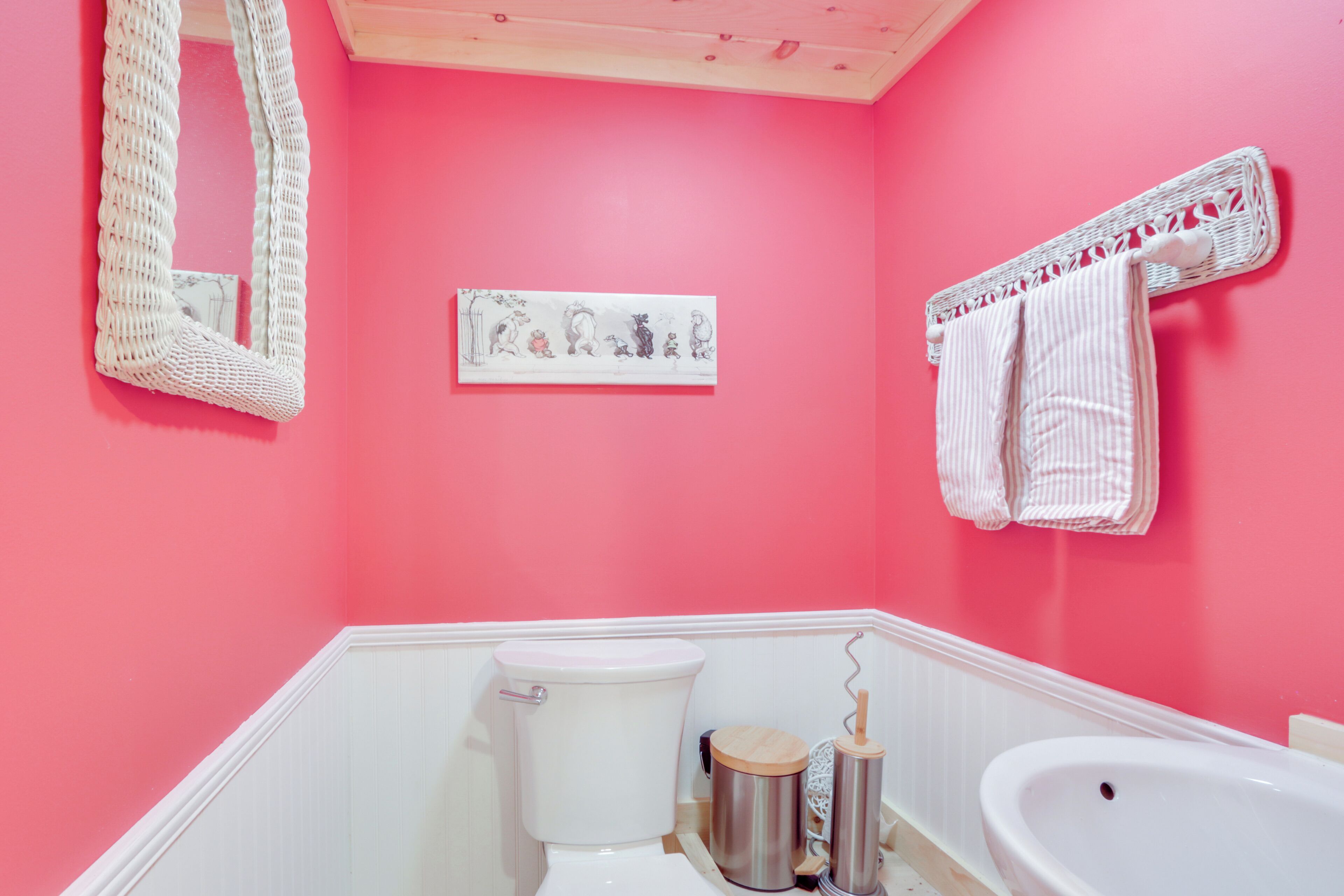 A bathroom with a pink wall, a white toilet, a sink, and a mirror.