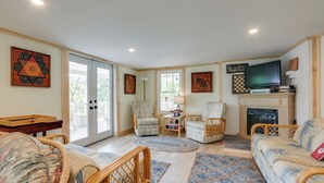 A cozy living room with wicker furniture, a flat-screen TV, and a fireplace. - River Views & Boat Launch Access: Huntingdon Home (Huntingdon)